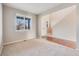 Open-concept area with neutral carpet and adjacent stairs, featuring a large window and a hallway at 10294 E Telluride Ct, Commerce City, CO 80022