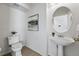 Bright half bathroom featuring a pedestal sink, round mirror, and minimalist decor at 13020 Grant W Cir # A, Thornton, CO 80241