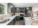 Modern kitchen with sleek, stainless appliances, tile backsplash, and beautiful green cabinets at 530 Everett St, Lakewood, CO 80226