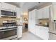 Modern kitchen featuring stainless steel appliances and white cabinetry, with dining room view at 2640 Overlook Dr, Broomfield, CO 80020