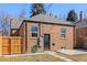 Exterior view of brick home with wooden fence, green hose, and utility boxes at 1467 Clermont St, Denver, CO 80220