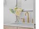 Close-up of a bathroom vanity with modern gold faucet, white counter, and decorative flower arrangement at 1467 Clermont St, Denver, CO 80220