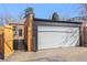 A white garage door with a brick building and wooden fence in a residential neighborhood at 1467 Clermont St, Denver, CO 80220