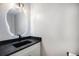 Stylish powder room featuring a vessel sink, modern faucet, lighted mirror, and white and dark finishes at 4431 W Jamison Pl, Littleton, CO 80128