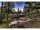 Aerial view of the home showcasing its landscaping, retaining wall, and wooded surroundings at 6100 Apache Dr, Larkspur, CO 80118