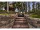 Outdoor seating area with stacked stone walls, forest backdrop, and two chairs at 6100 Apache Dr, Larkspur, CO 80118