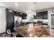Spacious kitchen boasts dark wood cabinetry, granite countertops, and stainless steel appliances at 18651 E 53Rd Ave, Denver, CO 80249