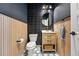 Stylish powder room with unique tile, wood paneling, modern fixtures, and oval mirror at 6237 Stable View St, Castle Pines, CO 80108
