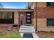 Close-up view of a home's front entrance, showcasing its modern door, brick facade, and well-maintained landscaping at 9025 W 4Th Ave, Lakewood, CO 80226