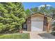 The garage of this home features brick and siding and a well-manicured lawn with a tree at 2208 Emery St, Longmont, CO 80501