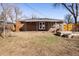 View of backyard with brick home, covered porch, and lawn with mature trees in the background at 7891 Maria St, Westminster, CO 80030