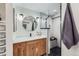 Stylish bathroom with a wooden vanity, round mirror, and a glass-enclosed shower with black and white tiling at 4441 N Meade St, Denver, CO 80211