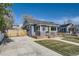 Exterior shot featuring a well-maintained lawn, paved driveway, gray siding, and a fenced yard at 4441 N Meade St, Denver, CO 80211