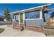 Charming home showcasing a gray exterior, brick foundation, and a striking green front door with modern glass panels at 4441 N Meade St, Denver, CO 80211