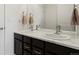 Bathroom featuring dual sinks with dark cabinets, marble countertops, and brushed nickel hardware at 5072 Lake Port Ave, Firestone, CO 80504