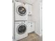 A bright laundry room features a stacked washer and dryer, white cabinetry, and wood-look tile flooring at 7995 E Mississippi Ave # A4, Denver, CO 80247