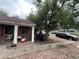 A view of the front of the house, showing the porch, yard with gravel, and surrounding trees and neighborhood street at 1900 Quebec St, Denver, CO 80220