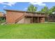 Brick home with an outdoor deck overlooking a large lawn at 7077 Dudley Dr, Arvada, CO 80004