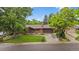 Charming brick ranch-style home with mature trees, lush green lawn, and an attached two-car garage at 7077 Dudley Dr, Arvada, CO 80004