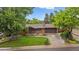 Charming brick ranch-style home with mature trees, lush green lawn, and an attached two-car garage at 7077 Dudley Dr, Arvada, CO 80004