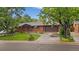 Charming brick ranch-style home with mature trees, lush green lawn, and an attached two-car garage at 7077 Dudley Dr, Arvada, CO 80004