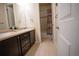 Well-lit bathroom with double sinks, tile flooring, and a shower with a decorative shower curtain at 25669 E Fair Dr, Aurora, CO 80016