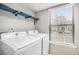 Bright laundry room featuring a blue shelf, a window with blinds and modern, front-loading Samsung washer and dryer at 4621 S Fraser Cir # B, Aurora, CO 80015