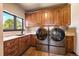 This laundry room boasts wooden cabinets, countertop space, a sink, and modern front-loading washer and dryer units at 1552 Colt Cir, Castle Rock, CO 80109