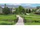 Scenic view of green lawns, walking path, and residential homes with mountains in the distance at 5448 El Diente St, Golden, CO 80403