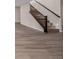 Basement stairs with wood railing and newel post, with recessed lighting on the wall at 56159 E Tomahawk Ave, Strasburg, CO 80136