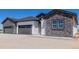 Home exterior showing attached three-car garage with stone and vertical siding at 56159 E Tomahawk Ave, Strasburg, CO 80136