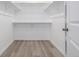 Bright walk-in closet with wood floor, white walls, and metal rods for optimal storage at 56159 E Tomahawk Ave, Strasburg, CO 80136