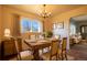 Warm dining room featuring a rustic wooden table, chandelier, and bright natural light with an open doorway to the living room at 971 Elm Pl, Thornton, CO 80229