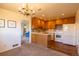 Open floor plan with kitchen featuring wood cabinets, stone countertops, and an adjacent dining area with chandelier at 971 Elm Pl, Thornton, CO 80229