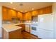 Well-lit kitchen featuring wooden cabinetry, sleek countertops, and modern white appliances at 971 Elm Pl, Thornton, CO 80229