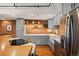 An industrial kitchen design with stainless appliances, white farm sink, grey cabinets, exposed pipes, and brick backsplash at 1801 Wynkoop St # 518, Denver, CO 80202