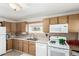 Galley kitchen with wood cabinets and white appliances at 5511 Leyden St, Commerce City, CO 80022