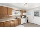 Kitchen with wood cabinets, white appliances, and a gas stove at 5511 Leyden St, Commerce City, CO 80022