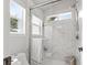 Bright bathroom featuring a glass-enclosed shower, white marble tile, and a sunlit window view at 1359 S Beeler Ct, Denver, CO 80247