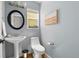 Powder room features pedestal sink, stylish round mirror, modern fixtures and beautiful wall art at 1359 S Beeler Ct, Denver, CO 80247