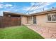 Cozy backyard featuring artificial turf, stone paver patio, fenced perimeter, and brick exterior at 2461 Yates St, Denver, CO 80212