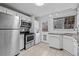Well-lit kitchen features stainless steel appliances, washer/dryer, white cabinets, and modern tile floors at 2461 Yates St, Denver, CO 80212
