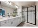 The bathroom has double sinks, a black framed shower, white cabinets, gray floors and white countertops at 8863 Osceola St, Westminster, CO 80031