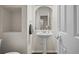 Chic half-bathroom with pedestal sink, arch mirror, and stylish fixtures enhancing the home's modern aesthetic at 4975 S Zephyr St, Littleton, CO 80123