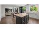 Open-concept kitchen with dark island, lots of cabinets, and stainless appliances seamlessly connects to the living room at 4975 S Zephyr St, Littleton, CO 80123