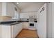 Efficient kitchen with white cabinets, a large refrigerator, and black tile counters at 19688 E Lasalle Dr, Aurora, CO 80013