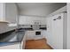 Compact kitchen featuring white cabinetry, black tile counters, and hardwood floors at 19688 E Lasalle Dr, Aurora, CO 80013