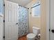 Small bathroom showcasing a toilet, floral shower curtain, and a single window at 5700 S Benton Cir, Littleton, CO 80123