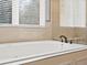 Close up of a soaking tub with granite surround and glass enclosed shower nearby at 5700 S Benton Cir, Littleton, CO 80123