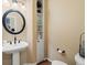 Stylish powder room with pedestal sink, round mirror, and built in storage at 5700 S Benton Cir, Littleton, CO 80123
